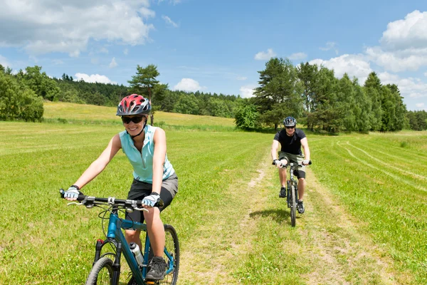 Sport paar mountainbikes op platteland rijden — Stockfoto