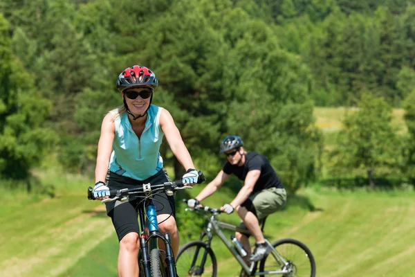 Sport mountain couple biking uphill sunny meadows — Stok fotoğraf