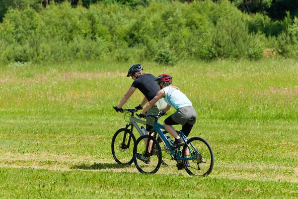 스포츠 산 커플 자전거 다운 힐 햇볕이 잘 드는 풀밭 — 스톡 사진