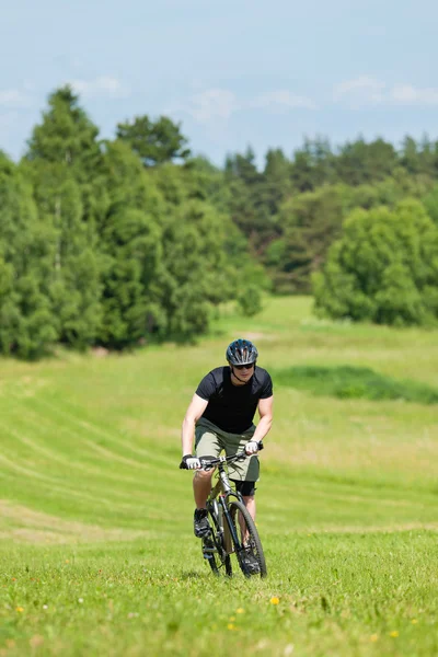 Homem esportivo mountain bike subida ensolarado prados — Fotografia de Stock