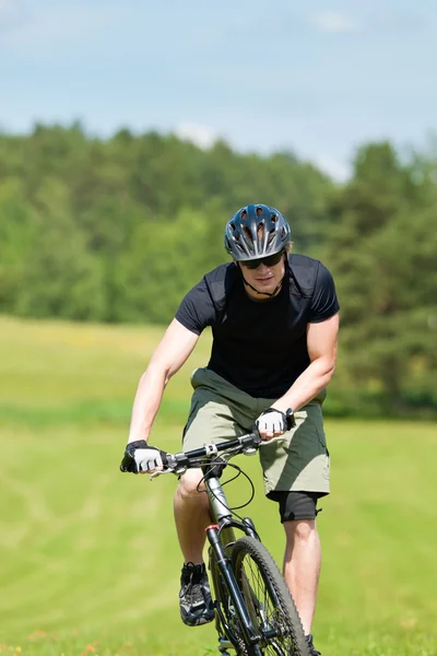 Sportig man mountainbike uppförsbacke soliga ängar — Stockfoto