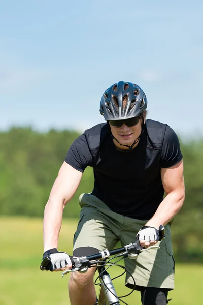 Sportive man mountain biking uphill sunny meadows — Stock Photo, Image