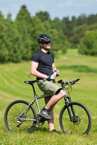 陽気な男マウンテン バイク リラックス日当たりの良い牧草地 — ストック写真