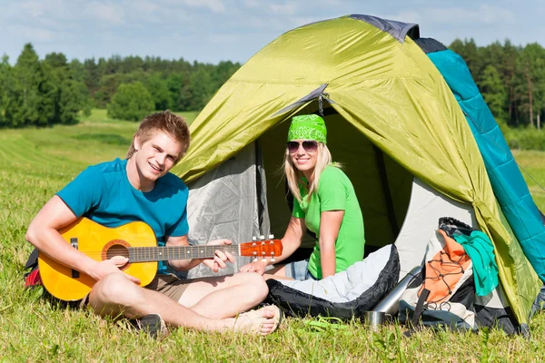 Camping casal tocando guitarra por tenda campo — Fotografia de Stock
