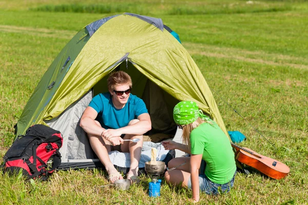 Giovane campeggio coppia cucinare pasto fuori tenda — Foto Stock