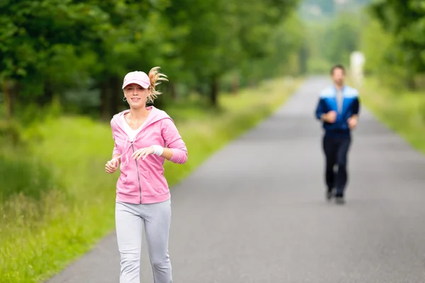 公園の道路を実行している陽気な若いカップルをジョギング — ストック写真