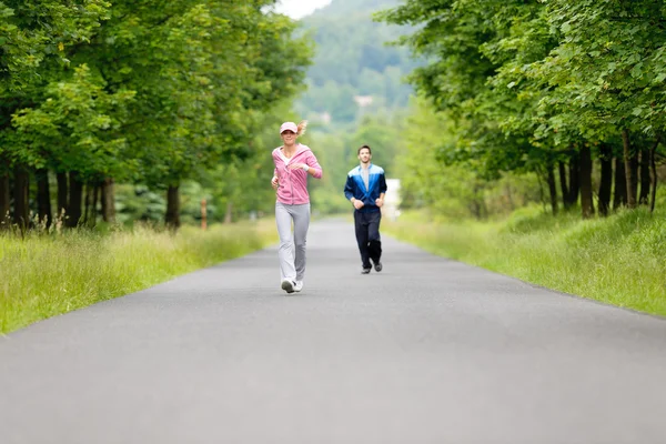 公園の道路を実行している陽気な若いカップルをジョギング — ストック写真