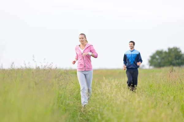 Jogging sportive young couple running meadow field — Stock Photo, Image