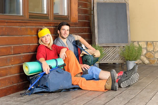 Tramping young couple backpack relax by cottage — Stock Photo, Image