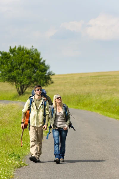 Caminhadas jovem casal mochila pisar estrada asfalto — Fotografia de Stock