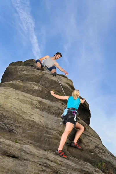 Frau klettert auf Felsen Mann hält Seil — Stockfoto
