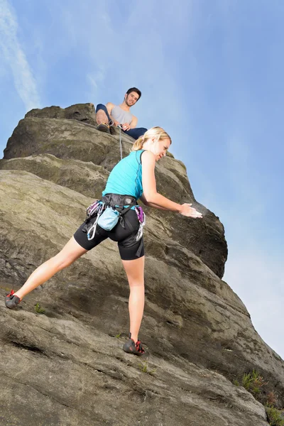 Mulher escalando até homem de rocha segurar corda — Fotografia de Stock