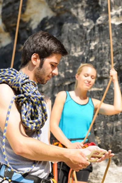 Скалолазный мужчина показывает женщине верёвочный узел — стоковое фото