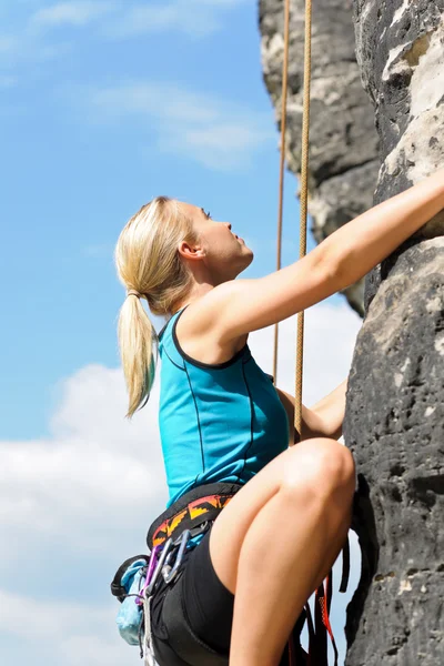 Rots klimmen blonde vrouw op touw zonnige — Stockfoto