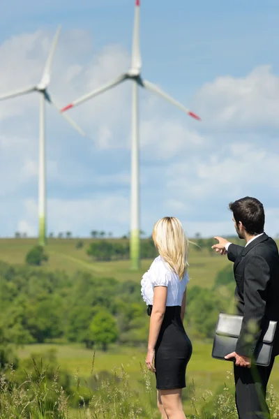 Empresarios de energía verde en campo muestran molino de viento — Foto de Stock