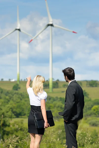 Green energy businesspeople in field show windmill — Stock Photo, Image