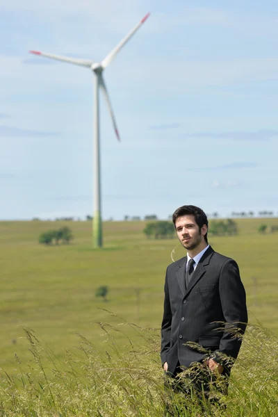 Green energy - Young businessman in field windmill — Stock Photo, Image