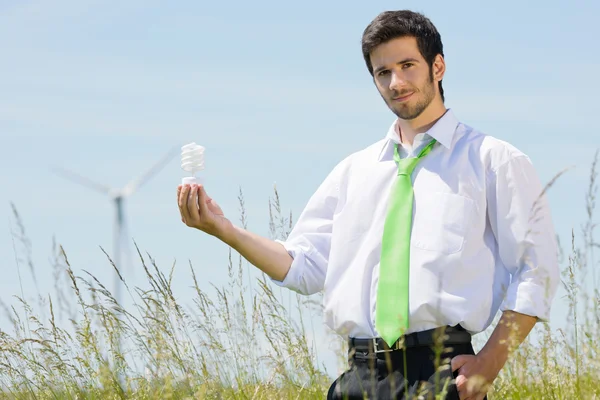 Green energy businessman in field hold bulb — Stock Photo, Image