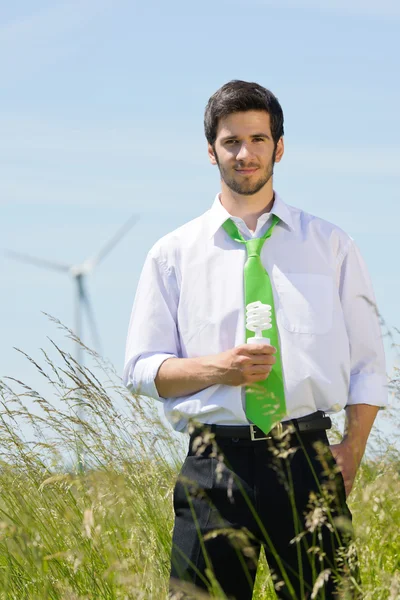 フィールドでのグリーン エネルギー実業家電球を保持します。 — ストック写真