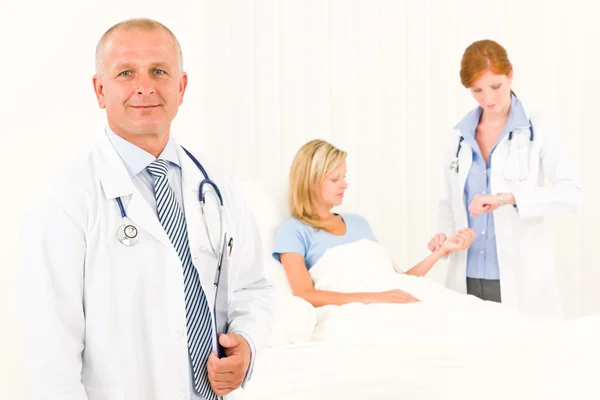 Два врача с пациентом лежат в постели — стоковое фото