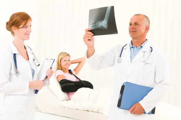 Les médecins regardent les rayons X patient bras cassé — Photo