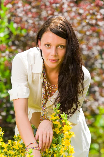 Vacker kvinna solig trädgård care gula blommor — Stockfoto