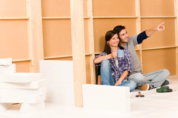 Покращення будинку молода пара розслабляє будівельну стіну — стокове фото