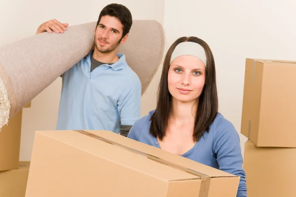 Casa movendo jovem casal caixas e carpete — Fotografia de Stock
