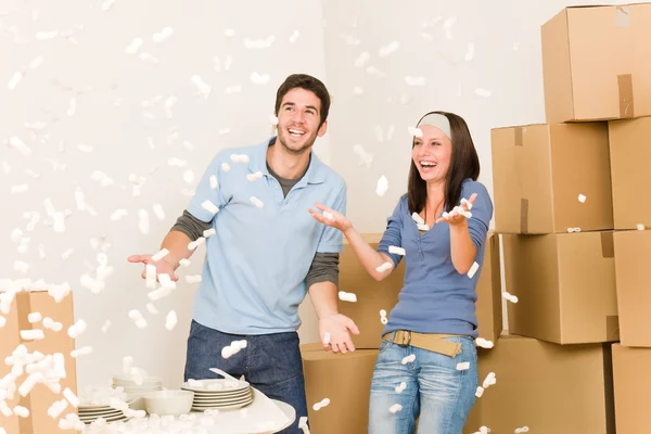 Mover a casa alegre pareja tirar poliestireno cacahuetes — Foto de Stock