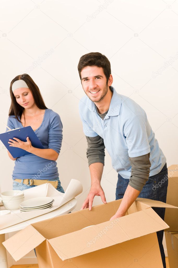 Moving home young happy couple unpacking boxes