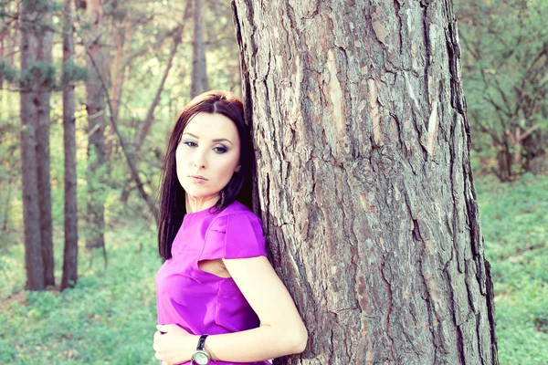 Krásná bruneta stojící poblíž stromu — Stock fotografie