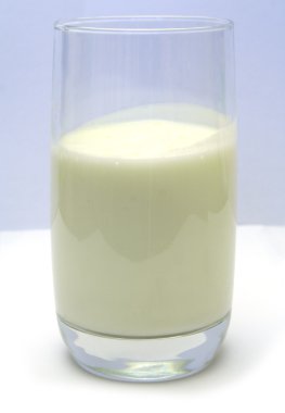 Glass with kefir on smooth white table clipart