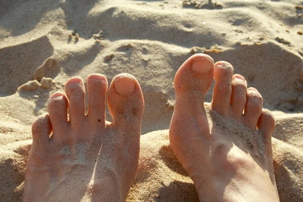 熱い砂の海岸に横たわっている人間の足 — ストック写真