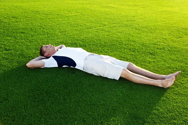 Genç adam relax bahar çimenlerin üzerinde — Stok fotoğraf