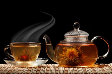 Glass teapot and a cup of green tea on a black background clipart