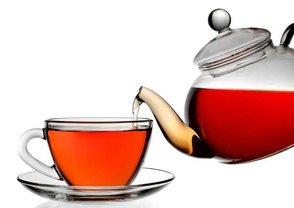 Té que se vierte en taza de té de vidrio aislado en un fondo blanco — Foto de Stock