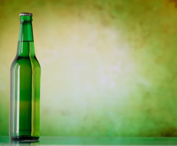 Uma garrafa de cerveja em um fundo verde — Fotografia de Stock