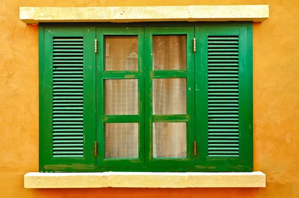 Зеленое окно на желтой стене — стоковое фото