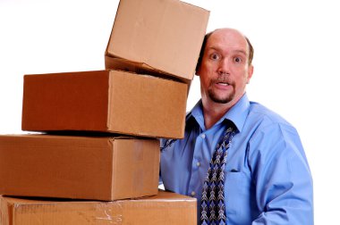 Man carrying heavy boxes with one about to fall. clipart