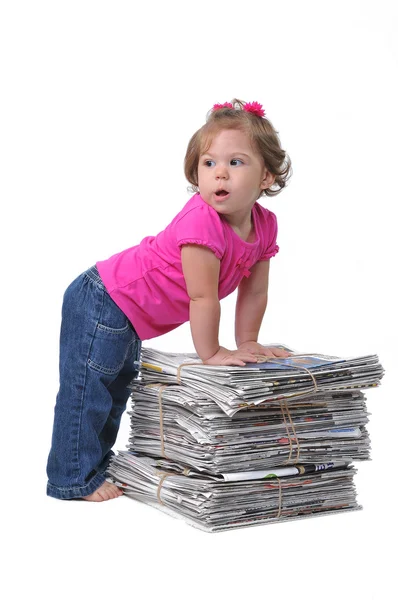 Bambino appoggiato contro pile di giornali — Foto Stock