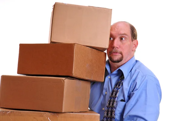 Чоловік несе важкі коробки, сподіваючись не скидати їх — стокове фото