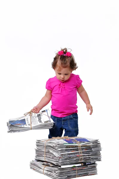 Pikkulapsi pitää hallussaan pinoa sanomalehteä kierrätystä varten tekijänoikeusvapaita kuvapankkikuvia