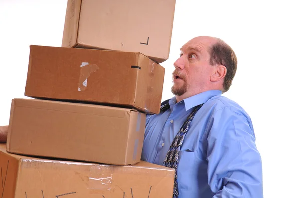 Mann trägt schwere Kisten in der Hoffnung, sie nicht fallen zu lassen. Stockbild