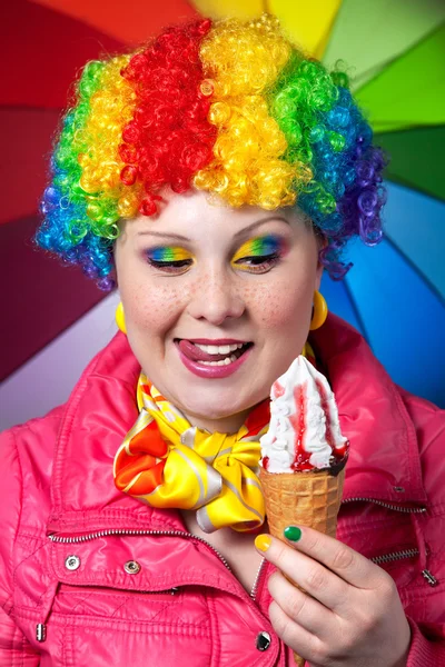 Clown with rainbow make up eating ice cream