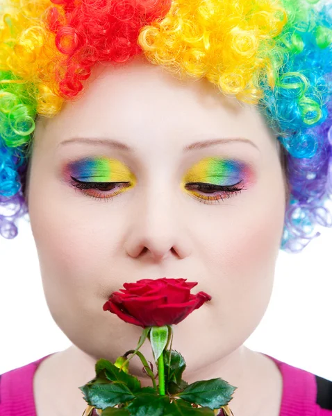 Clown with rainbow make up smelling rose — Stock Photo, Image