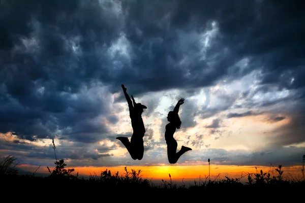 Пара силуэтов, прыгающих на закате — стоковое фото