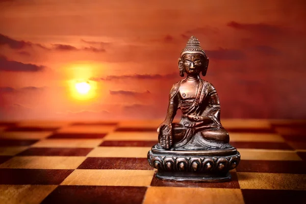 Бронзовый Будда на полу шахматного стола — стоковое фото