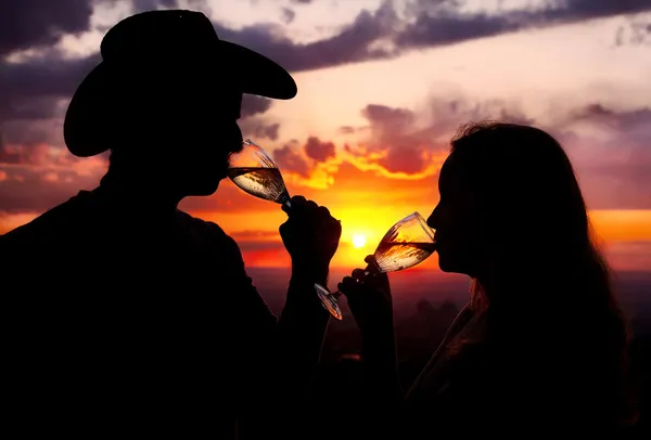 Silhuetas de casal bebendo champanhe ao pôr do sol — Fotografia de Stock