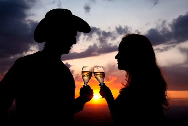 Couple Silhouettes clanging glasses at sunset — Stock Photo, Image