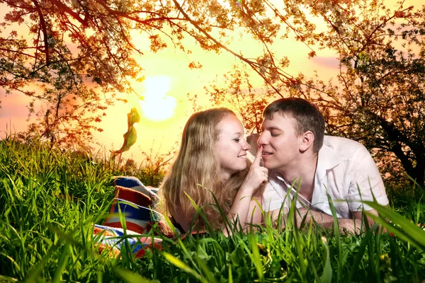 Couple on green grass at sunset — Stock Photo, Image